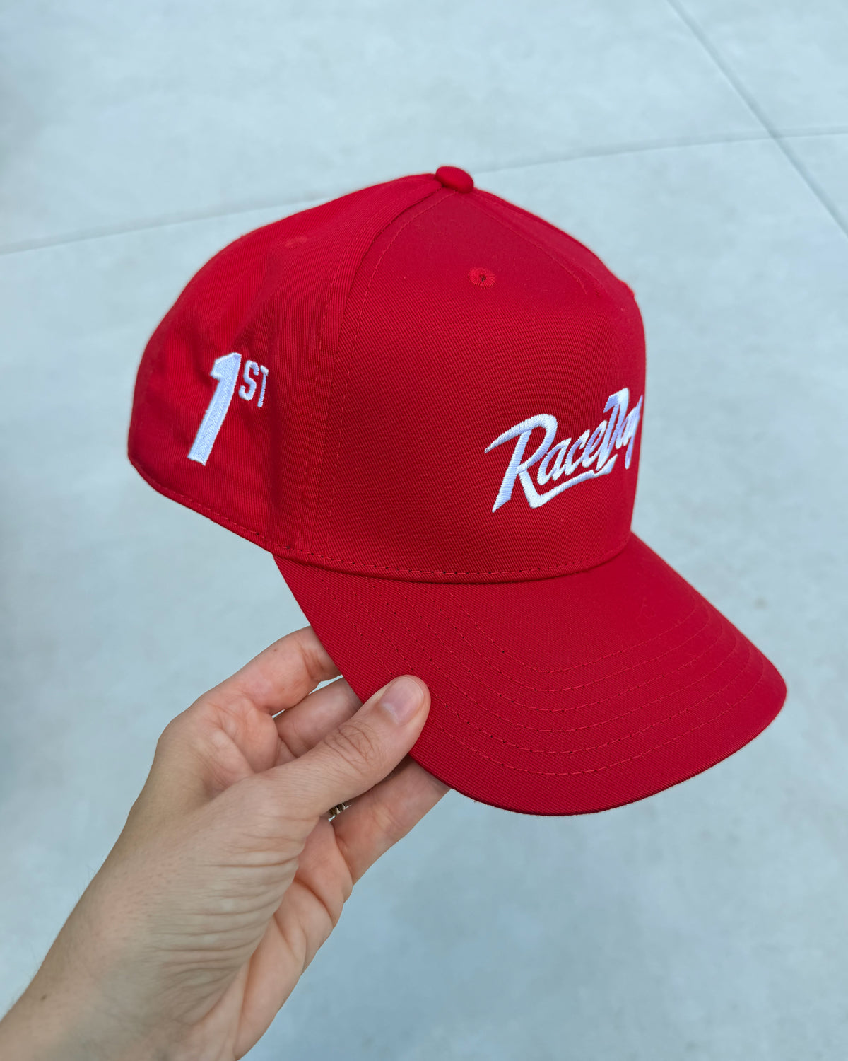 Hand holding RaceDay Hat Victory at an angle