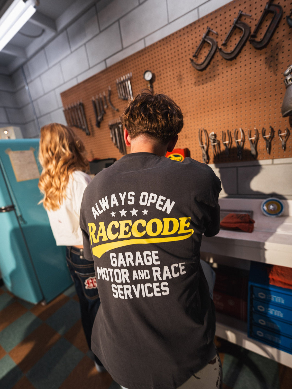 Garage Tee Dark Grey with the «Always Open» back print at the workbench in the Race Code garage