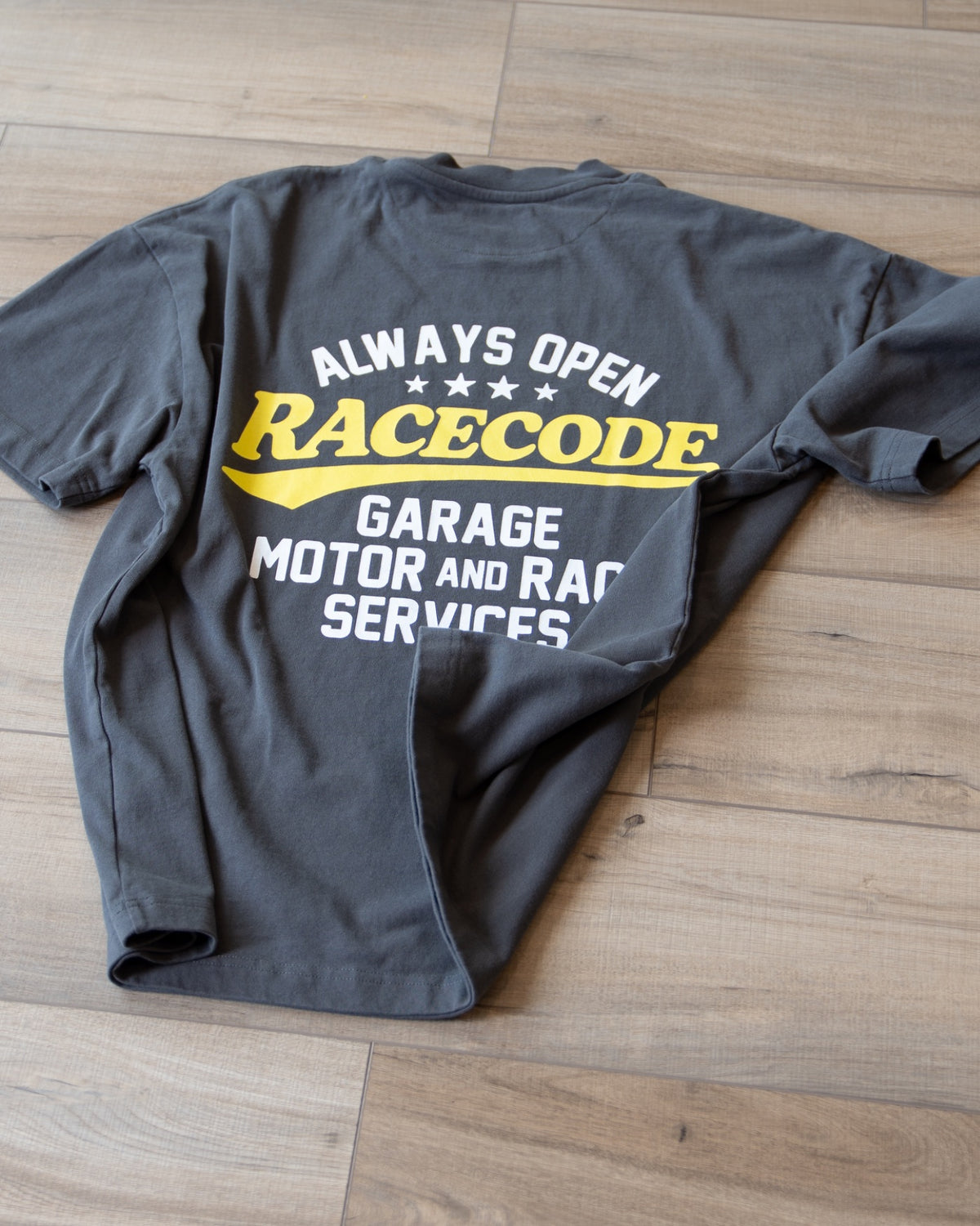 Garage Tee Dark Grey laid flat, «Always Open» back print